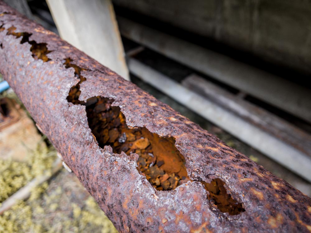 cast-iron Rusted cast iron pipe that has aged with a large crack in it.